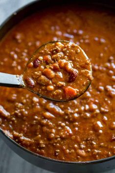 a spoon full of chili and beans in a pot