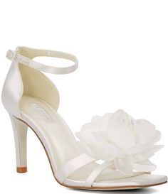 a women's white wedding shoe with a flower on the heel