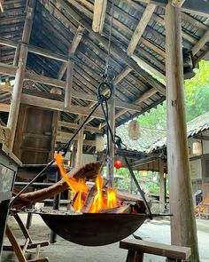 an outdoor fire pit in the middle of a building with wood beams and roofing