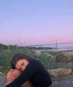 a woman is sitting on the ground with her head in her hands and looking at the camera