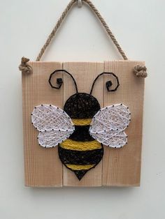 a wooden sign with a black and yellow bee on it's side hanging from a rope