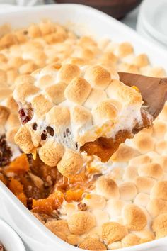 a wooden spoon is lifting a scoopful of baked dessert from a casserole dish