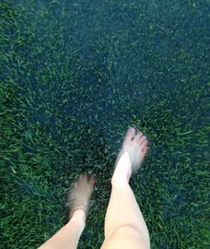 a person standing in the grass with their feet up