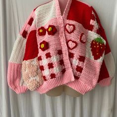 a pink and red knitted sweater hanging on a mannequin