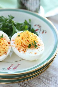 two deviled eggs on a plate with parsley and seasoning sprinkles