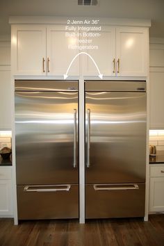 two stainless steel refrigerators side by side in a kitchen with white cabinets and wood flooring