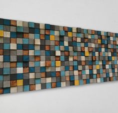 a wooden wall hanging on the side of a white wall with blue, yellow and brown tiles