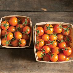 two baskets filled with tomatoes sitting on top of a wooden table next to each other