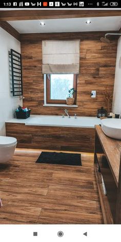 a bathroom with wooden flooring and white bathtub next to two sinks in front of a window