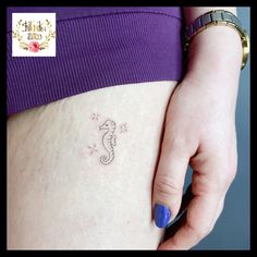 a woman's stomach with a small seahorse tattoo on her left side belly