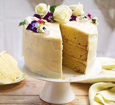 a white cake with two slices cut out and flowers on top, sitting on a plate