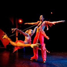 two dancers performing on stage with one holding the pole