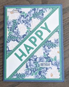 a happy birthday card with flowers and ribbon on the front, sitting on a wooden surface