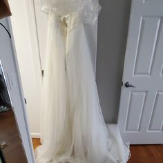 a white wedding dress hanging on a door