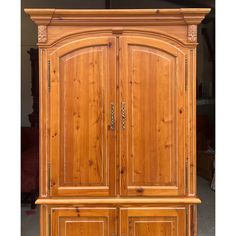 a wooden armoire with two doors and drawers