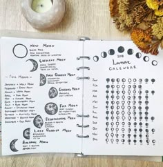 an open notebook with moon phases on it next to some flowers and a small candle