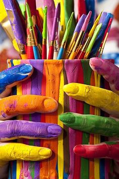 colorful crayons are arranged in a basket with fingers and feet painted on them