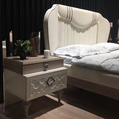 a white bed sitting next to a night stand on top of a hard wood floor