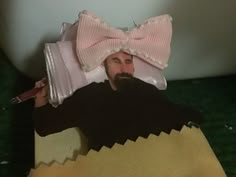 a man with a pink bow on his head is laying in a bathtub and holding a toothbrush