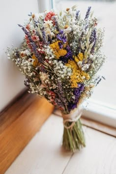 a bouquet of wildflowers sits in front of a window