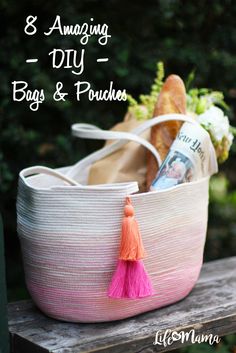 a pink and white basket with tassels on it sitting on top of a wooden table