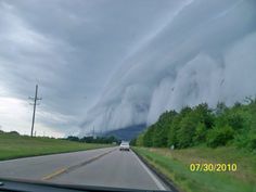 a car driving down a road under a storm cloud