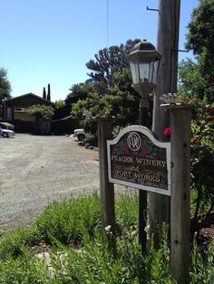 a wooden sign sitting on the side of a road next to a street light and trees