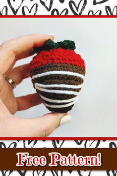 a hand holding a knitted strawberry ornament with the words free pattern on it