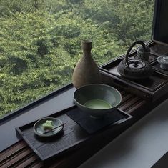 there is a bowl, tea pot and plate on the window sill in this room