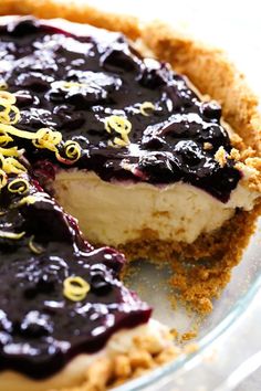 a blueberry cheesecake is cut in half on a glass pie plate with one slice taken out