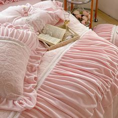 a bed with pink bedspread, pillows and a book on top of it