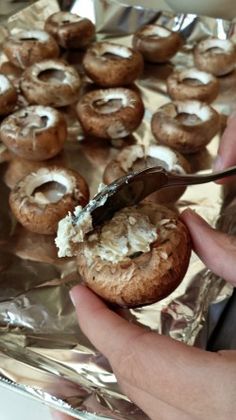 a person is spreading icing onto some cookies on aluminum foil with a spatula