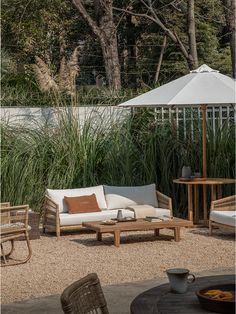 an outdoor seating area with chairs, tables and umbrellas in front of some tall grass