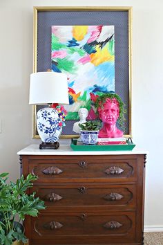 a dresser with two vases on top of it and a painting above the drawers