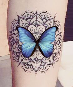 a blue butterfly sitting on the side of a woman's leg with intricate designs