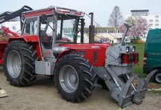 a red tractor parked next to a green truck