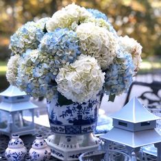 a blue and white vase filled with flowers sitting on top of a table next to candles