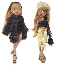 two dolls dressed in gold and black outfits, one is holding a handbag while the other has a purse