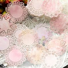 pink doily sitting on top of a white plate next to some flowers and fruit