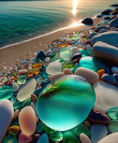 the sun is setting over some rocks and glass pebbles on the beach by the water