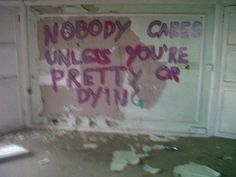 a dirty room with graffiti written on the wall