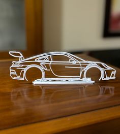 a paper model of a car sitting on top of a wooden table next to a mirror