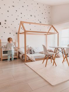 a child standing in front of a bed with stars on the wall