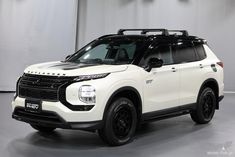 a white suv is parked in front of a gray wall with black lettering on it