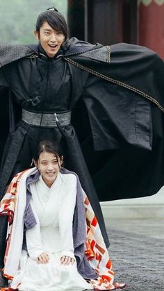 two young people dressed in costumes posing for a photo with one holding the other's coat