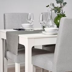 a white table with two chairs and some wine glasses