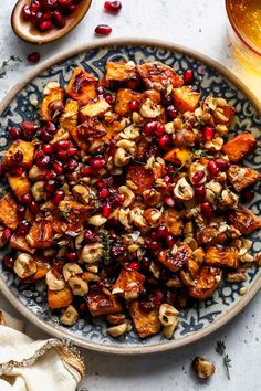 a bowl filled with nuts and pomegranates next to a glass of beer