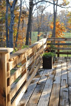 a wooden deck with potted plants on the side and trees in the background,