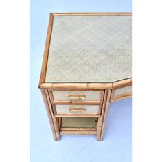 an old bamboo desk with drawers and glass top on the bottom, against a blue background