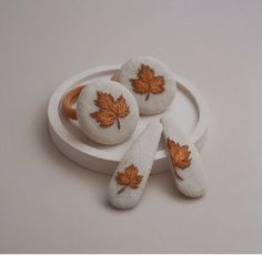 three pieces of cloth with leaves on them sitting on a white plate next to each other